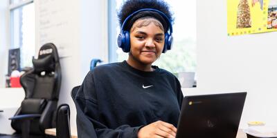 student working on a laptop, wearing headphones