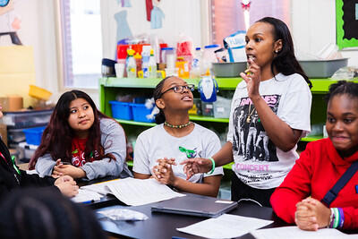 teacher/school leader talking with students around a table