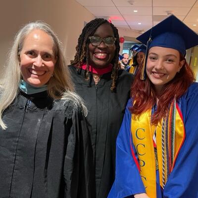 Liv Birnstad is smiling in her graduation attire alongside two leaders in Capital City Public Charter School.