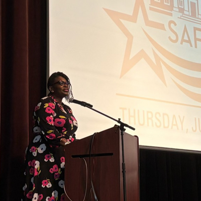 a black woman in a dress standing at a podium on a stage