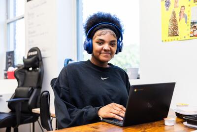 student working on a laptop, wearing headphones